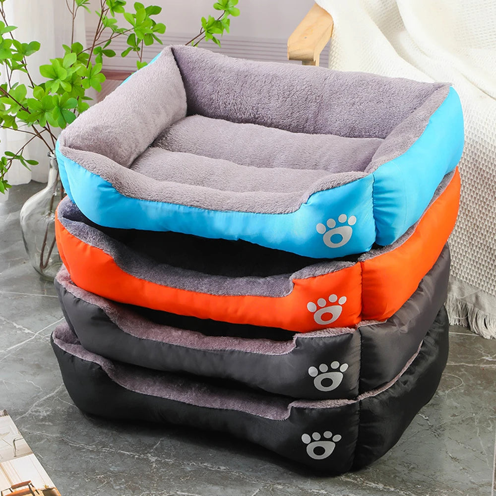 Stack of plush rectangular dog beds in blue, orange, and gray with paw print design